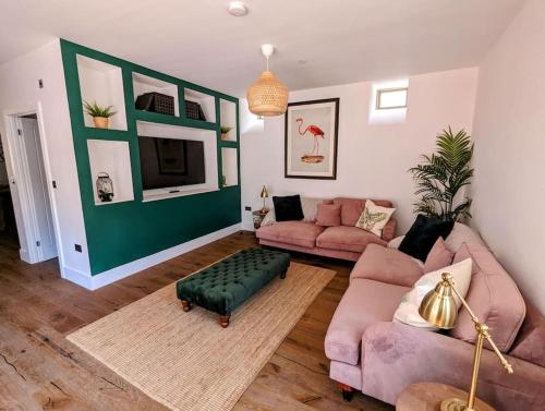 a living room with pink furniture and a green wall at The Livery Cottage at Cefn Tilla Court, Usk in Usk