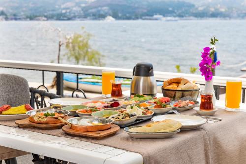 a table with plates of food on a table near the water at Elite Hotel Yalıkavak in Yalıkavak