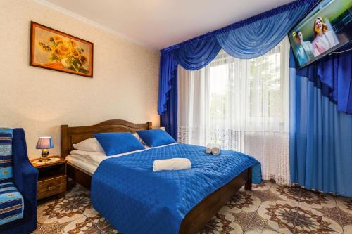 a bedroom with a bed with blue sheets and a window at Willa ROZA in Łeba