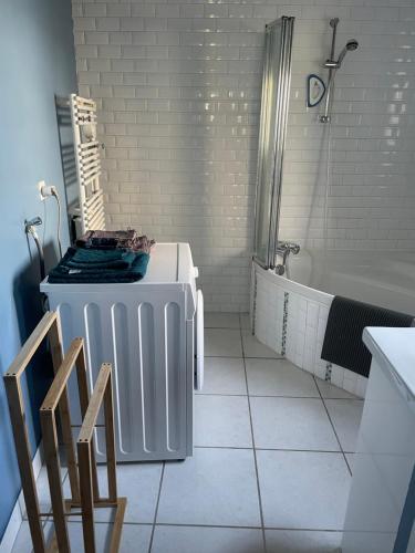 een witte badkamer met een bad en een douche bij Ty Auguste, petite maison bretonne in Plobannalec-Lesconil