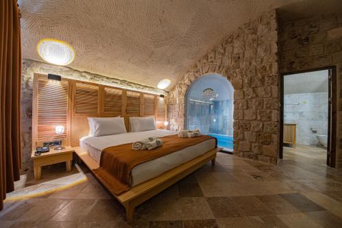 a bedroom with a large bed in a stone wall at Cappadocia Hobbit House in Nevşehir