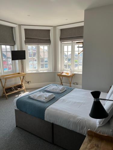 ein Schlafzimmer mit einem Bett in einem Zimmer mit Fenstern in der Unterkunft The Bay in Pevensey