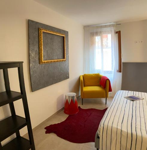 a bedroom with a bed and a yellow chair at CasaBella Chioggia in Chioggia