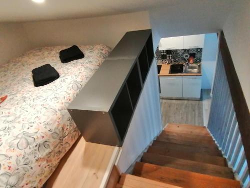 een slaapkamer met een bed en een trap met een keuken bij Le Grain de Sable, studio avec mezzanine in Tonneins