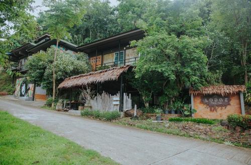 a house with a thatched roof on a street at Lodge Phang nga boutique in Ban Khaek