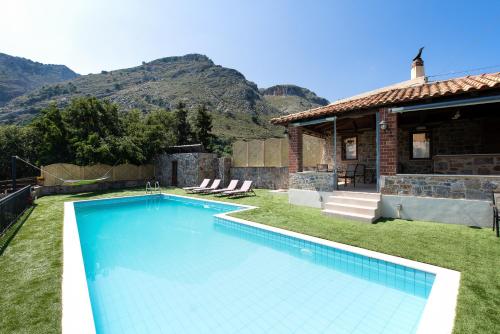 a swimming pool in front of a house with mountains at Metohi Nature Living in Kastamonítsa