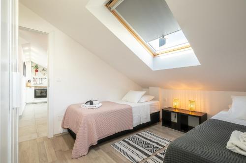 een slaapkamer op zolder met 2 bedden en een dakraam bij Apartments Karisima2 in Korčula