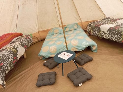 Plouray的住宿－tente nature，配有桌子、枕头和雨伞的帐篷