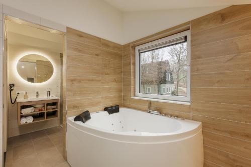 ein großes Bad mit einer Badewanne und einem Fenster in der Unterkunft Center Parcs Eifel Mosel Nürburgring in Gunderath