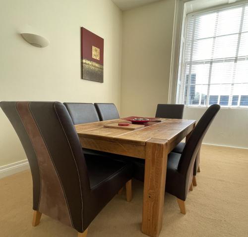 a dining room table with black chairs and a wooden table at Manor Court in Penzance