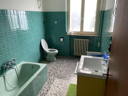baño verde con bañera, aseo y lavamanos en La casa matta, en Verucchio