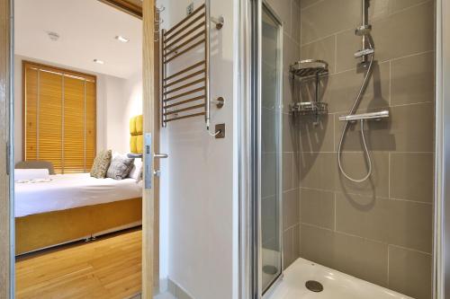 łazienka z prysznicem oraz sypialnia z łóżkiem w obiekcie Imperial Piccadilly Apartments w Londynie