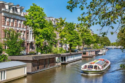 ein Boot, das einen Fluss hinunter in einer Stadt fährt in der Unterkunft Amstel Corner Hotel in Amsterdam