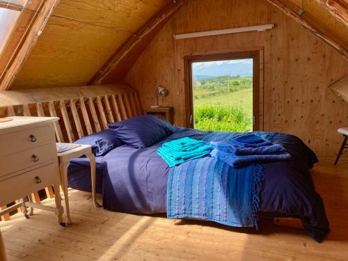 a bed in a wooden room with a window at Creative Art Cabin, Causeway Coast, beach 10 mins in Articlave