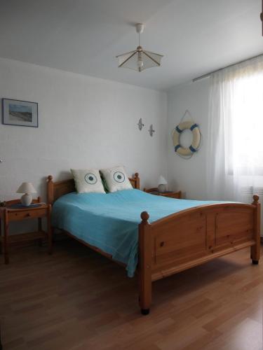 une chambre avec un lit avec des draps bleus et une fenêtre dans l'établissement Maison de famille sur l'île d'Oléron, à Dolus-d'Oléron