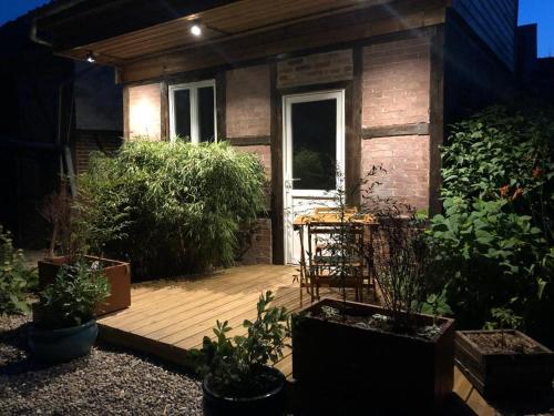 una piccola casa con una terrazza in legno con piante di La chambre de l'abreuvoir a Bergicourt