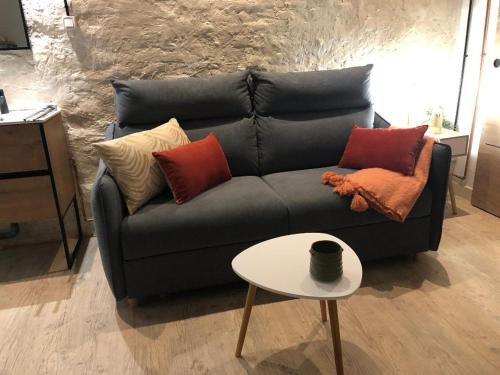 - un canapé noir avec des oreillers et une table dans le salon dans l'établissement La chambre de l'abreuvoir, à Bergicourt