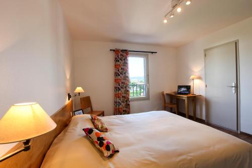 a bedroom with a bed with a lamp and a window at Logis Hotel Le Nouvel in Portes-lès-Valence