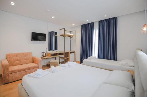 a hotel room with two beds and a chair at Otto Hotel in Ksamil