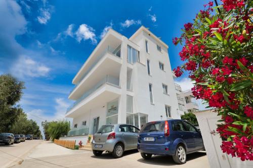 two cars parked in front of a white house at Otto Hotel in Ksamil
