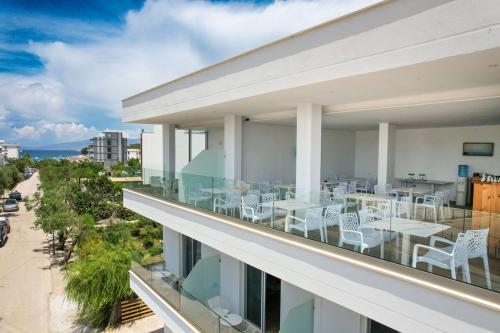a balcony with white chairs and tables on a building at Otto Hotel in Ksamil