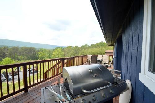 a grill on the side of a house on a deck at Black Bear Cabin - Fire Pit, Grill, View, Pet Friendly, Fireplace, King Bed, Wifi, Game Room in Morton Grove