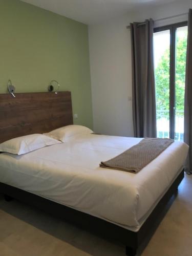 a large bed in a bedroom with a window at Hôtel du Golfe Pinarello in Pinarellu