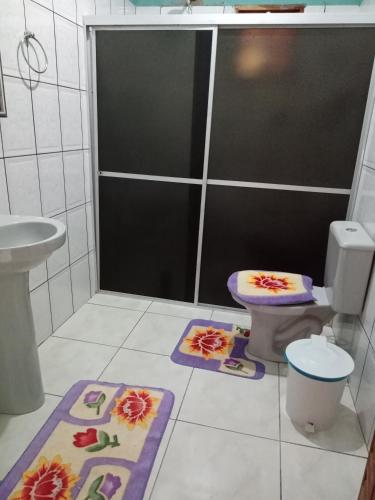 a bathroom with a toilet and two mats on the floor at Pousada Recanto da Villa in Mucugê
