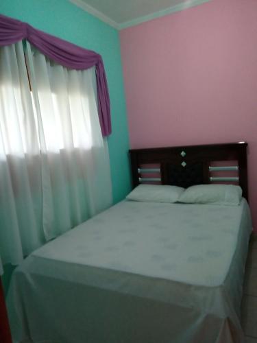 a bedroom with a bed and a window with white curtains at Pousada Recanto da Villa in Mucugê