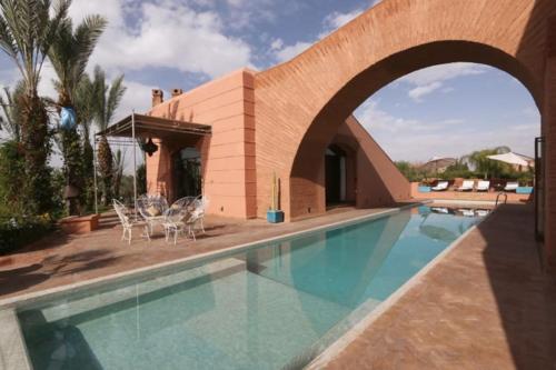a house with a swimming pool and a building at Villa Jolyamelkis - golf Marrakech in Marrakesh