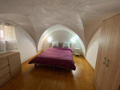 een slaapkamer met een paars bed op een zolder bij La casa sotto il castello! in Carovigno
