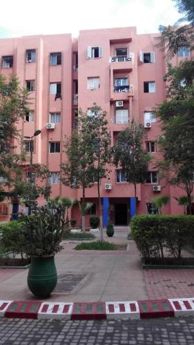 een groot roze gebouw met bomen ervoor bij appartement cosy à Marrakech in Marrakesh