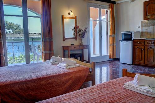 a bedroom with two beds and a kitchen with a balcony at Hotel Benitses Arches in Benitses