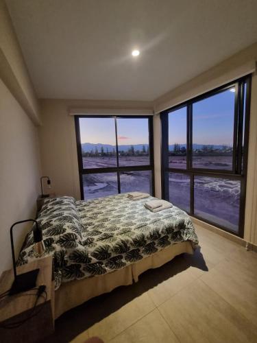1 dormitorio con 1 cama y 2 ventanas grandes en Moderno apartamento con vista a la Cordillera en Luján de Cuyo
