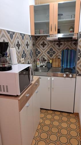 a kitchen with white cabinets and a microwave at Apartmani Belsito in Lovran
