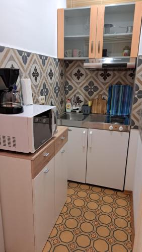 a kitchen with white cabinets and a microwave at Apartmani Belsito in Lovran