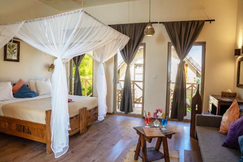 a bedroom with a canopy bed and a living room at Clove Island Villas & Spa in Makunduchi