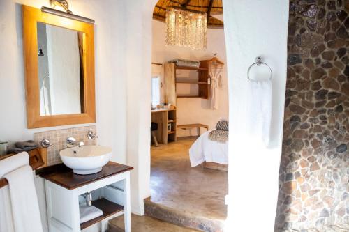a bathroom with a sink and a mirror and a bedroom at Qambathi Mountain Lodge in Kamberg Valley