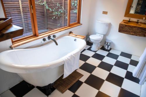 a bathroom with a white tub and a checkered floor at Qambathi Mountain Lodge in Kamberg Valley