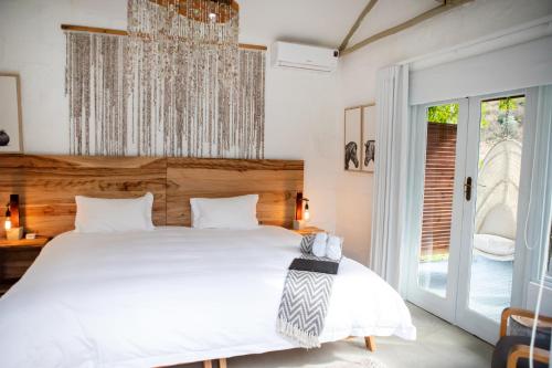 a bedroom with a large white bed and a window at Qambathi Mountain Lodge in Kamberg Valley