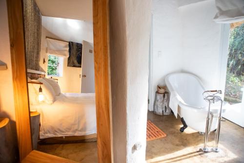 a bathroom with a bath tub and a bed at Qambathi Mountain Lodge in Kamberg Valley