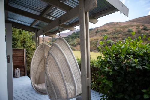 two wicker chairs hanging from a porch with a view at Qambathi Mountain Lodge in Kamberg Valley