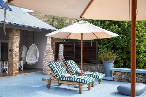 two chairs and an umbrella on a patio at Qambathi Mountain Lodge in Kamberg Valley