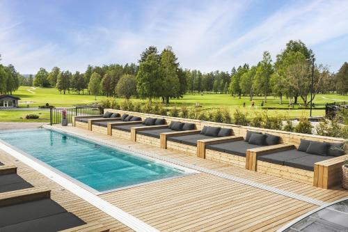 um pátio com uma piscina e espreguiçadeiras ao lado de um campo em Lannalodge em Vintrosa