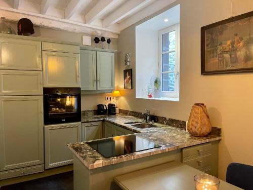 cocina con armarios blancos y encimera de granito en Petit gîte d’arrière-cour au pied du Château, en Combourg