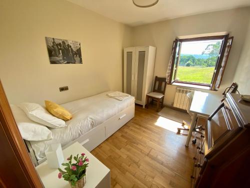 Una pequeña habitación con una cama y una ventana. en Villa Paraes, en Nava