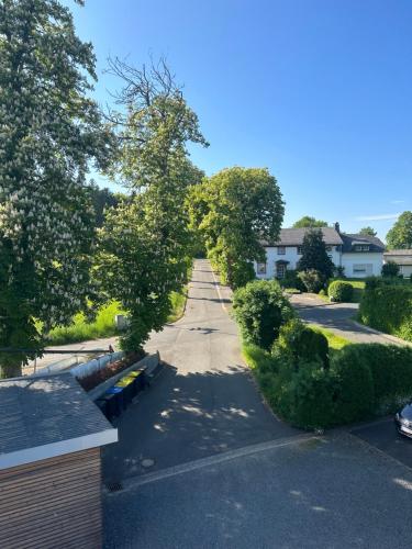 an empty street in a residential neighborhood with trees at Gleis 1, Eisenbahn Waggon mit Whirlpool und Ofen in Dahlem
