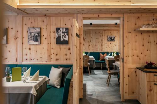 a restaurant with wooden walls and a green bench at Vitaurina Royal Hotel in Molini di Tures