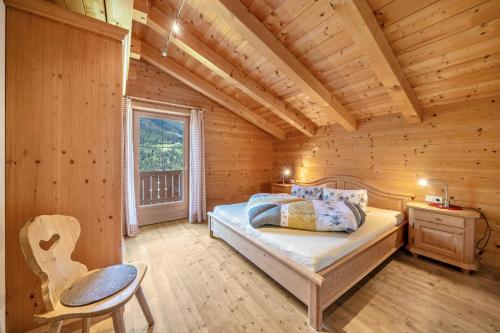 a bedroom in a log cabin with a bed and a chair at Marschalkhof Sankt Helena in Motini al Rio