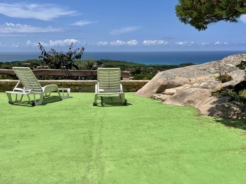 two chairs sitting on a lawn with the ocean in the background at Residence Rena Majore in Rena Majore